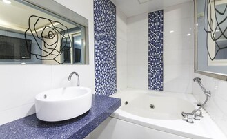 Un baño moderno con un lavamanos blanco, una bañera y azulejos de mosaico azules en las paredes.