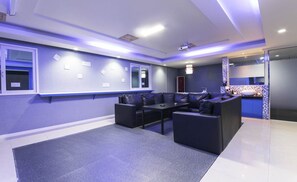 A modern room with a projector screen, seating area, and a small table. - Songjeong V Hotel (Busan)