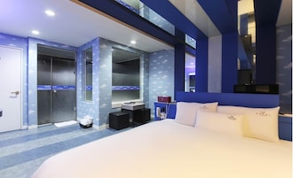 Una habitación de hotel moderna con una cama grande, un tocador con espejo, un vestidor y un baño con ducha e inodoro.