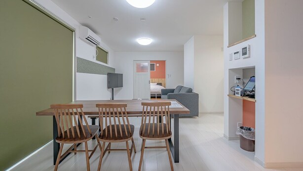 Una cocina moderna con comedor, un sofá gris y un televisor pequeño.