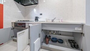 Una cocina compacta con horno integrado, microondas y campana extractora de acero inoxidable.