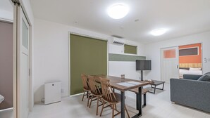 Una habitación moderna y bien iluminada con una mesa de comedor y sillas, un sofá y una televisión.