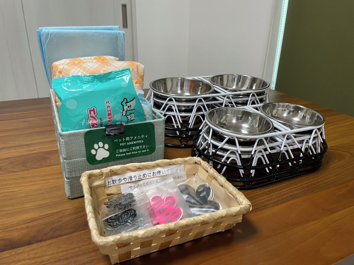 A dining table with pet amenities including a pet bed, bowls, and a basket with pet food and toys.