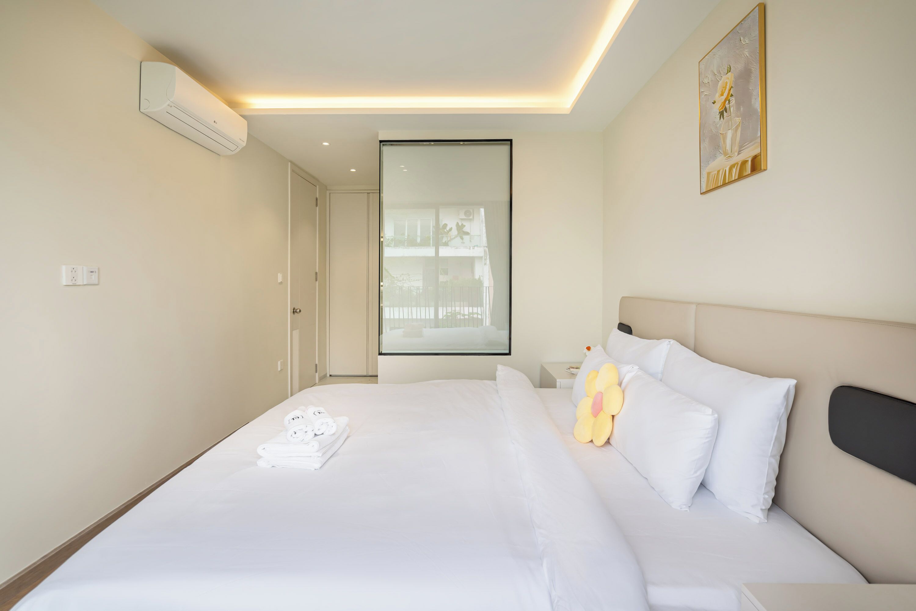 A hotel room with a large bed, a bedside table, a plush toy, and a painting on the wall.