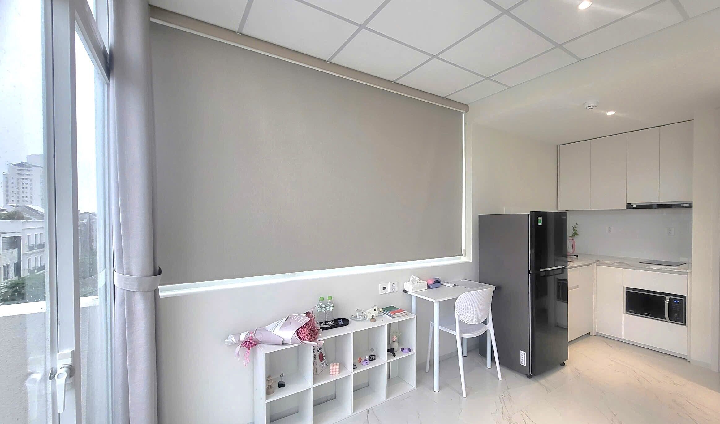 A modern kitchen with a black refrigerator, white cabinets, and a small dining table with chairs.
