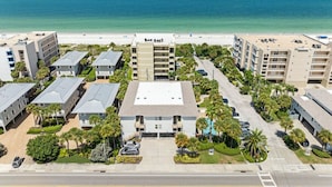 A multi-story hotel with a central courtyard, parking, and a beach view.
