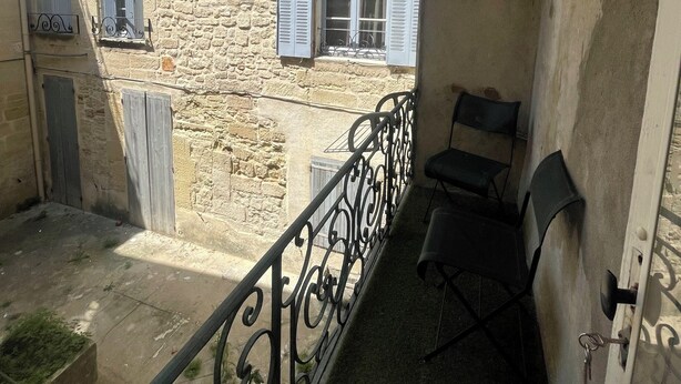 A balcony with a wrought iron railing, a stone building with blue shutters, and a door with a key in the lock. - Appartement Centre-ville (Uzès)