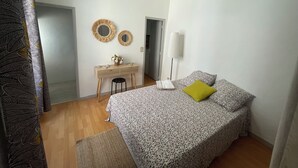 A bedroom with a bed, a desk, two mirrors, a lamp, and a window. - Appartement Centre-ville (Uzès)