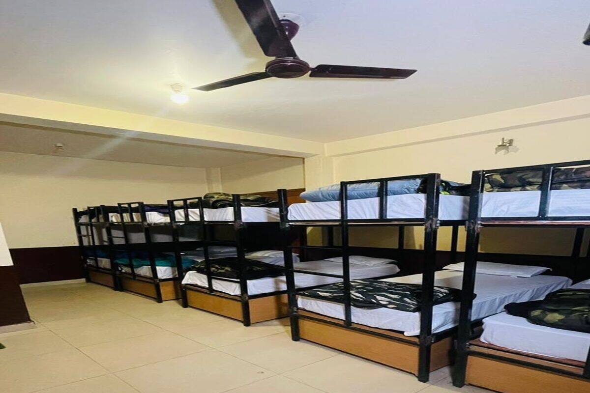 A dormitory room with bunk beds, a ceiling fan, and a tiled floor.
