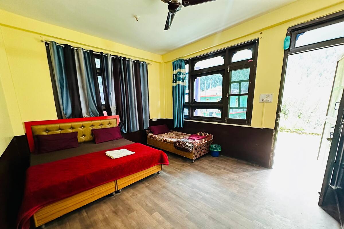 A bedroom with a large bed, a smaller bed, a window with curtains, and a door.