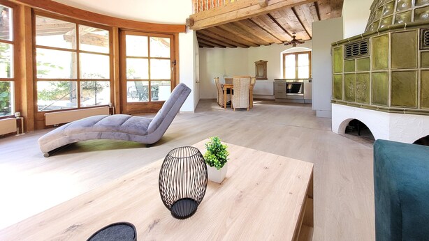 A spacious living area with a curved sofa, a dining table with chairs, a small plant, and a kitchen in the background. - Vacation apartment 6 for max. 4 persons (Berchtesgaden)