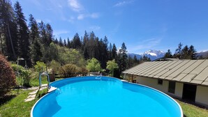 A round swimming pool with a metal ladder, surrounded by a grassy area and trees. - Vacation apartment 6 for max. 4 persons (Berchtesgaden)