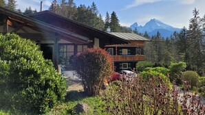 A wooden chalet with a balcony, surrounded by lush greenery and a mountain backdrop. - Vacation apartment 6 for max. 4 persons (Berchtesgaden)