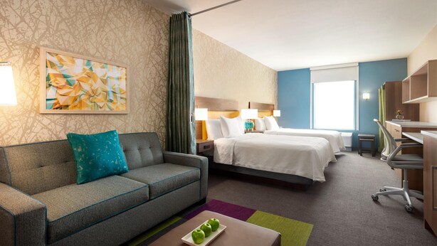 Ein Hotelzimmer mit einer Couch, einem Bett, einem Schreibtisch und einem Bild an der Wand.