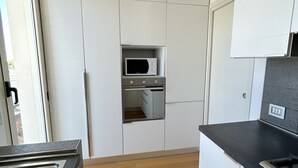 Een moderne keuken met witte kastjes, een ingebouwde magnetron en een oven.