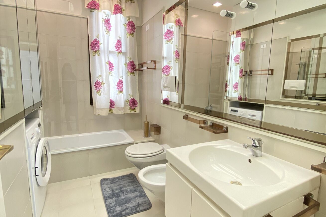 A modern bathroom with a bathtub, toilet, bidet, and a large sink.