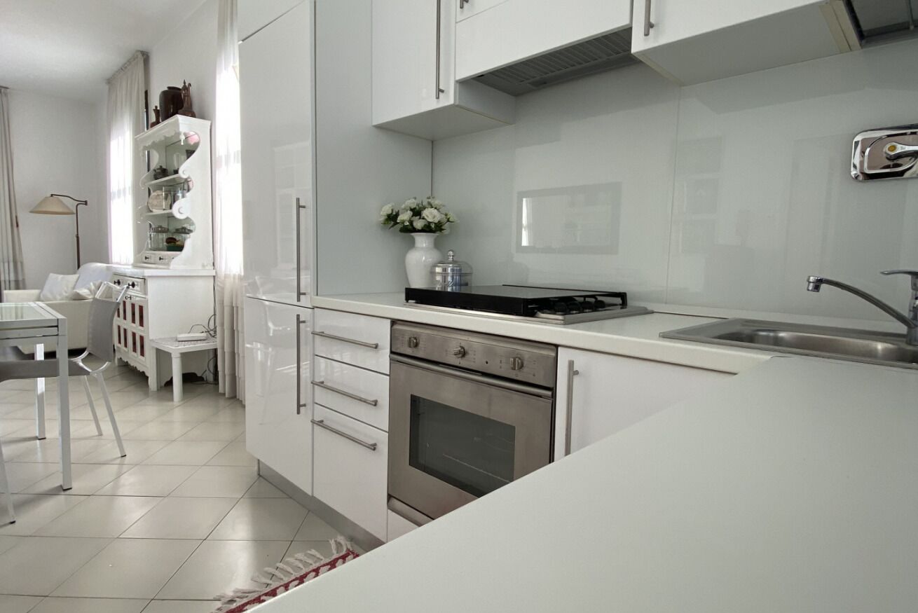 A modern kitchen with white cabinetry, a stainless steel oven, and a black countertop.