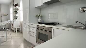 A modern kitchen with white cabinetry, a stainless steel oven, and a black countertop.