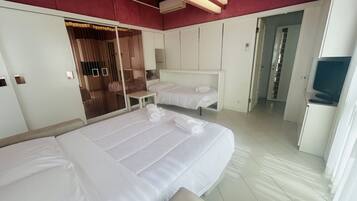 Habitación de hotel con dos camas, un armario, un escritorio y un televisor.