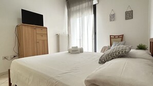 Une chambre à coucher comprenant un lit, une armoire en bois, un téléviseur à écran plat posé sur le dessus, un radiateur et deux éléments de décoration murale.