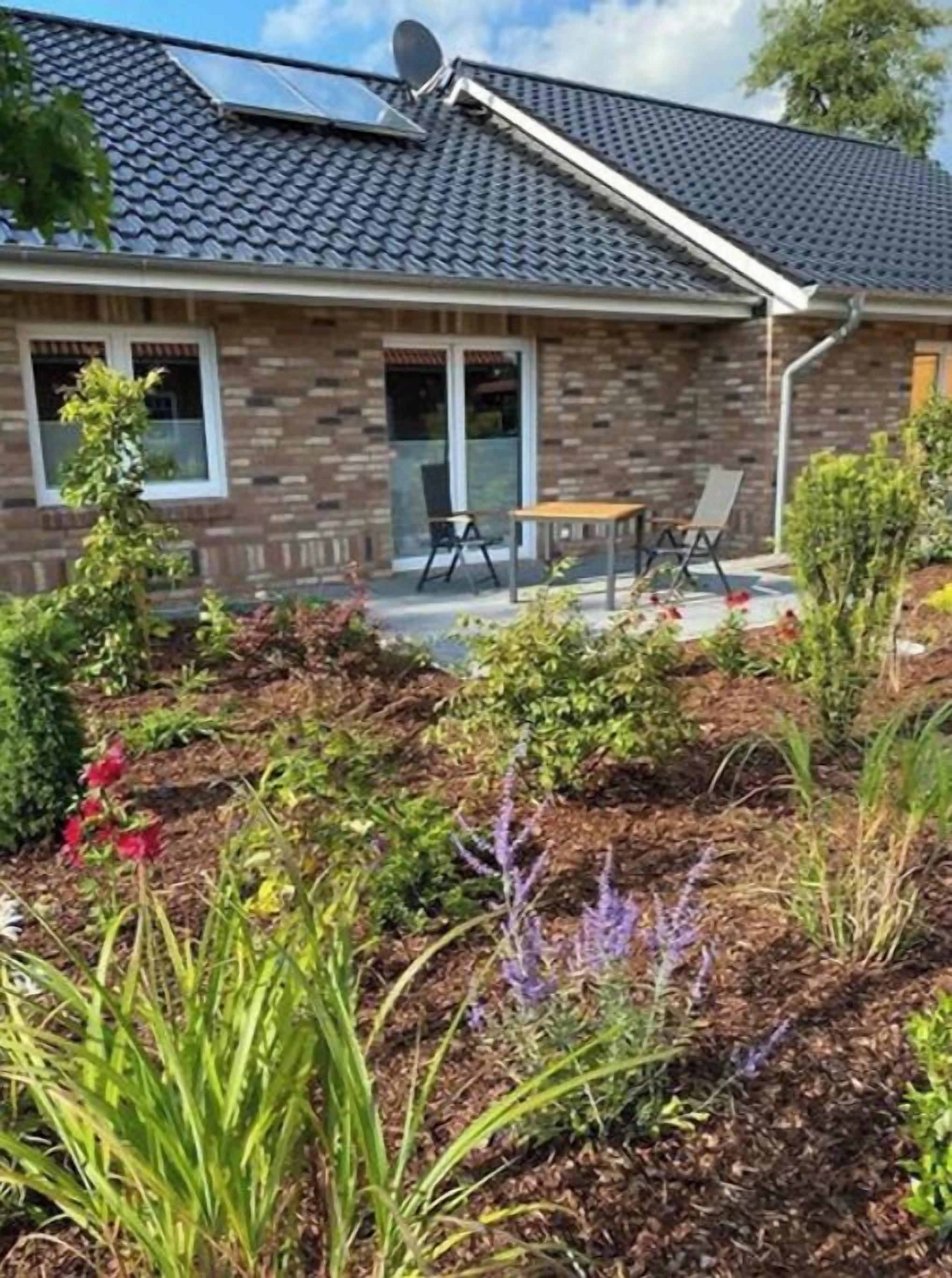 Una casa con fachada de ladrillo, tejado de tejas y un patio con mobiliario exterior.