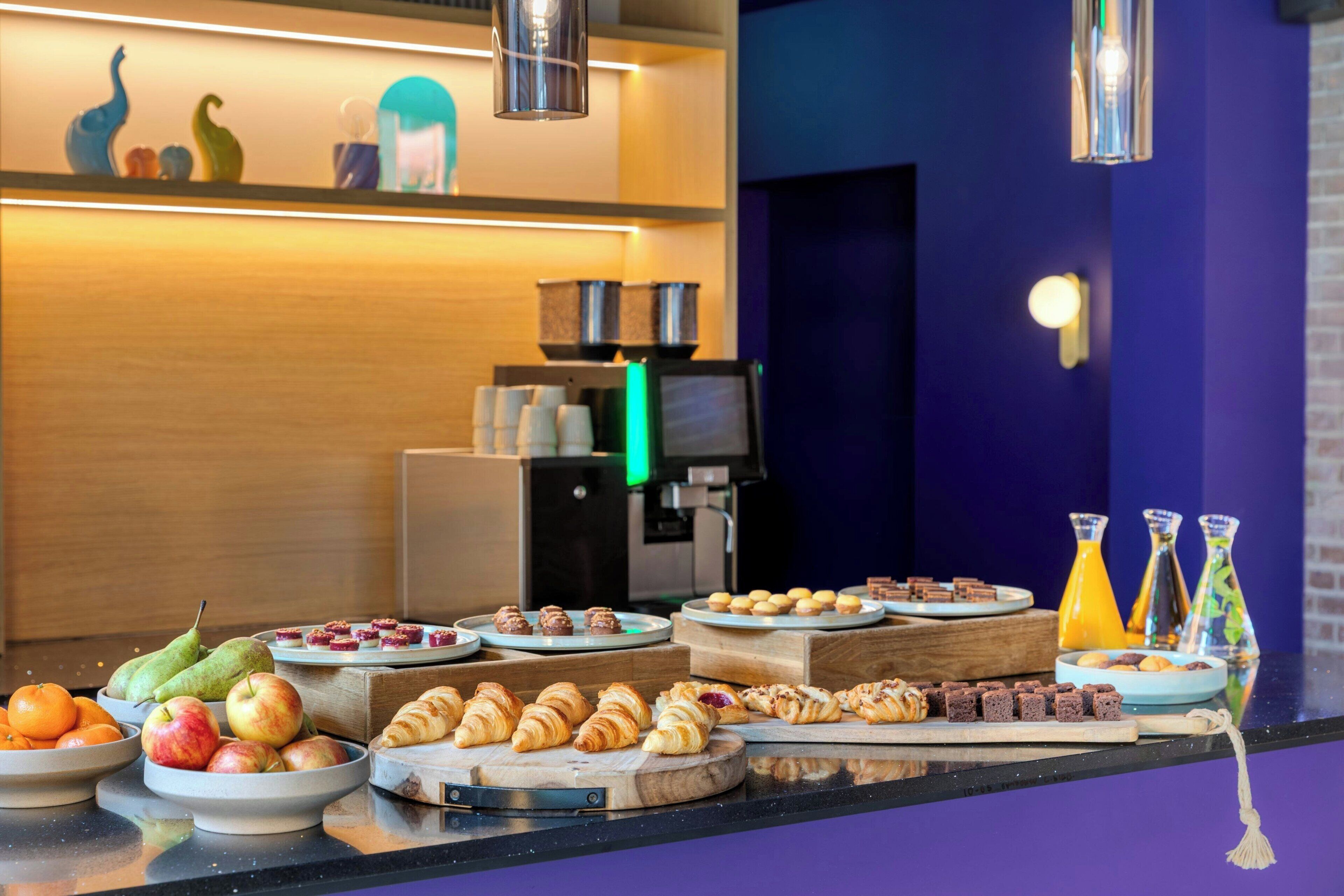 A breakfast buffet with various pastries, fruits, and beverages.