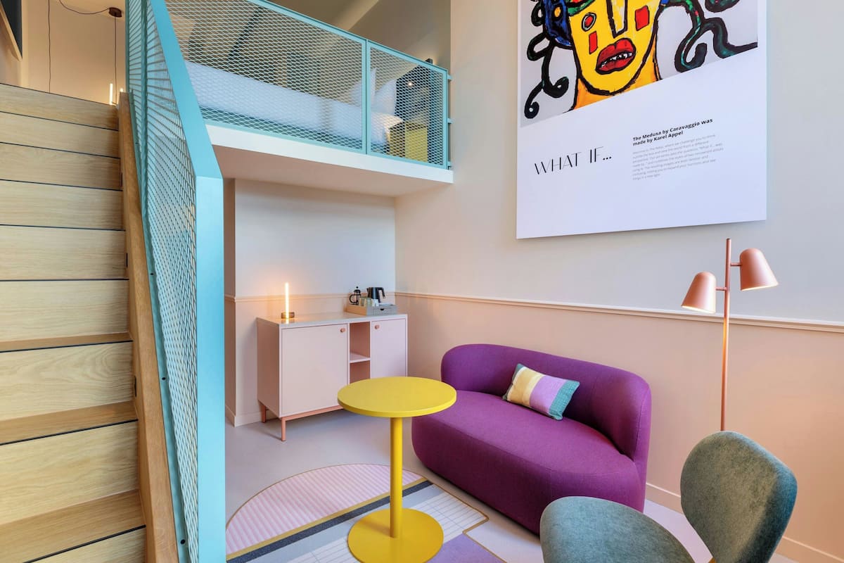 A modern interior with a wooden staircase, a purple sofa, a small yellow table, and a white cabinet.