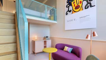 A modern interior with a wooden staircase, a purple sofa, a small yellow table, and a white cabinet.