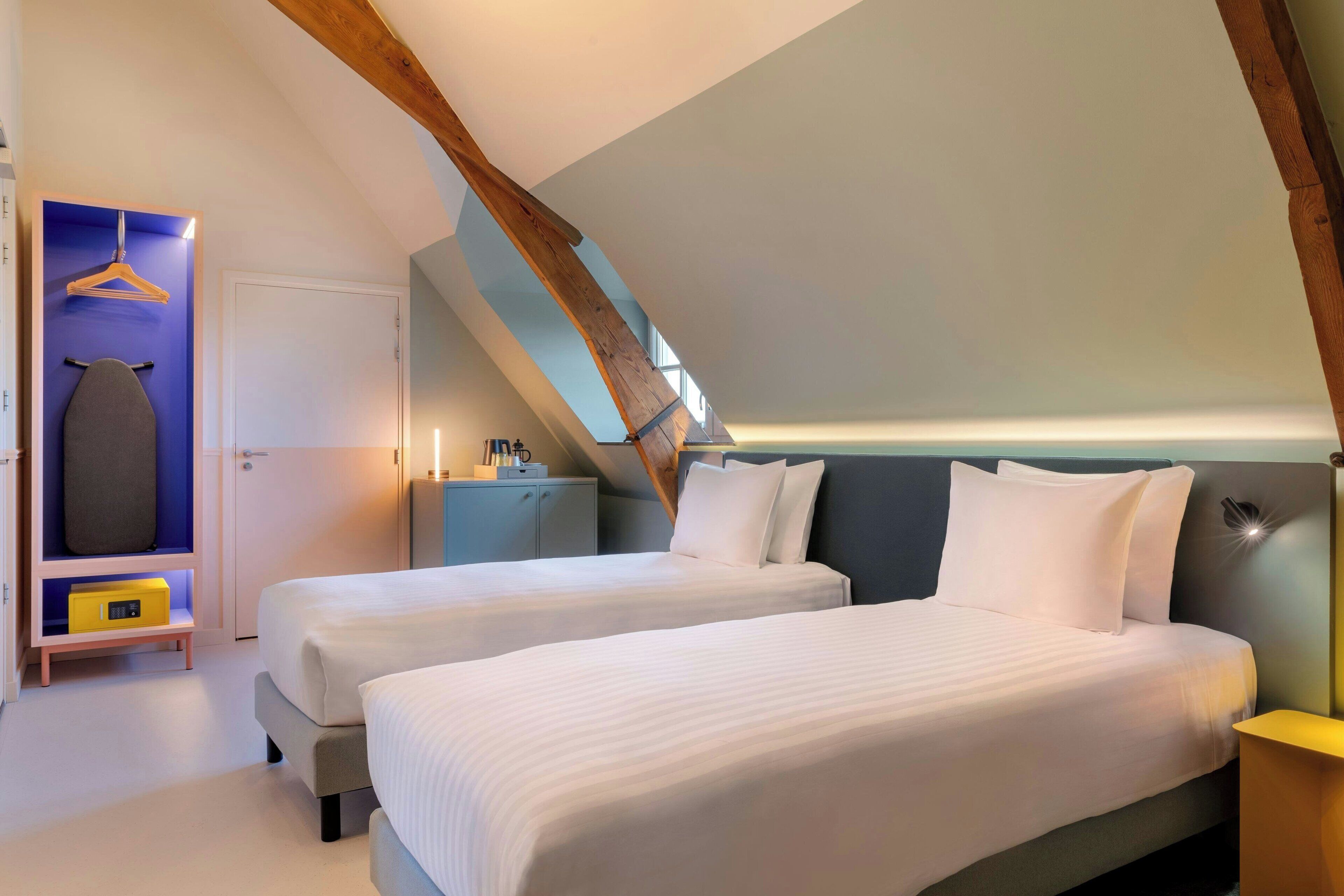 A bedroom with two beds, a wardrobe, and a desk.