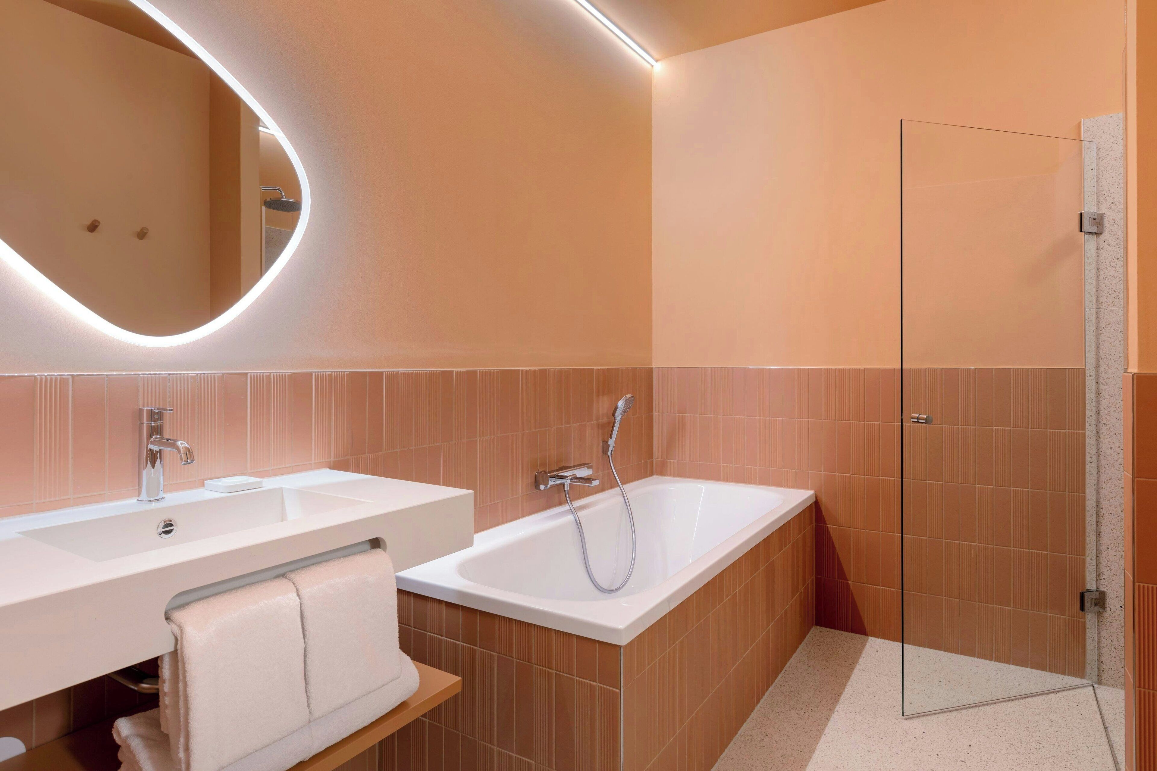 Een moderne badkamer met een grote spiegel, twee wasbakken, een bad en een douchecabine van glas.