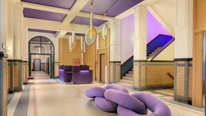 Una hall con reception, una scala e un'area salotto unica in tonalità viola.