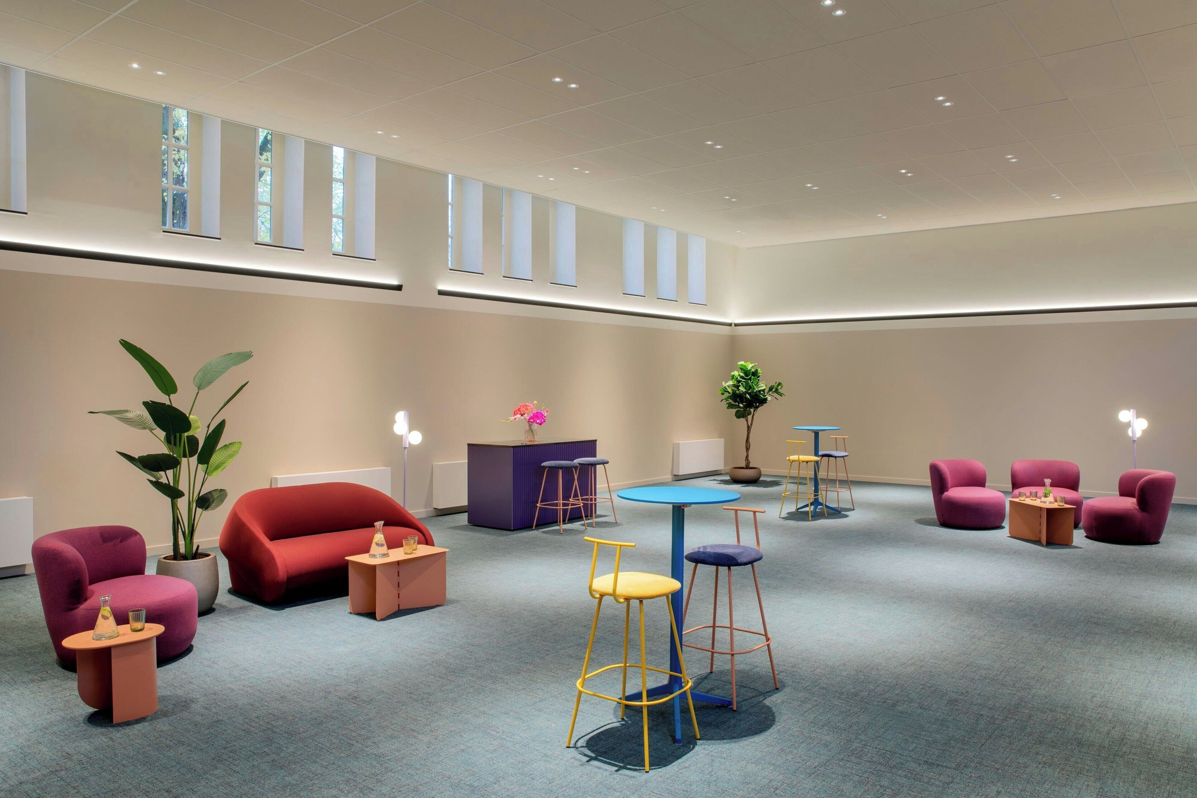 A spacious lobby with a high ceiling, multiple seating areas, and a central plant.