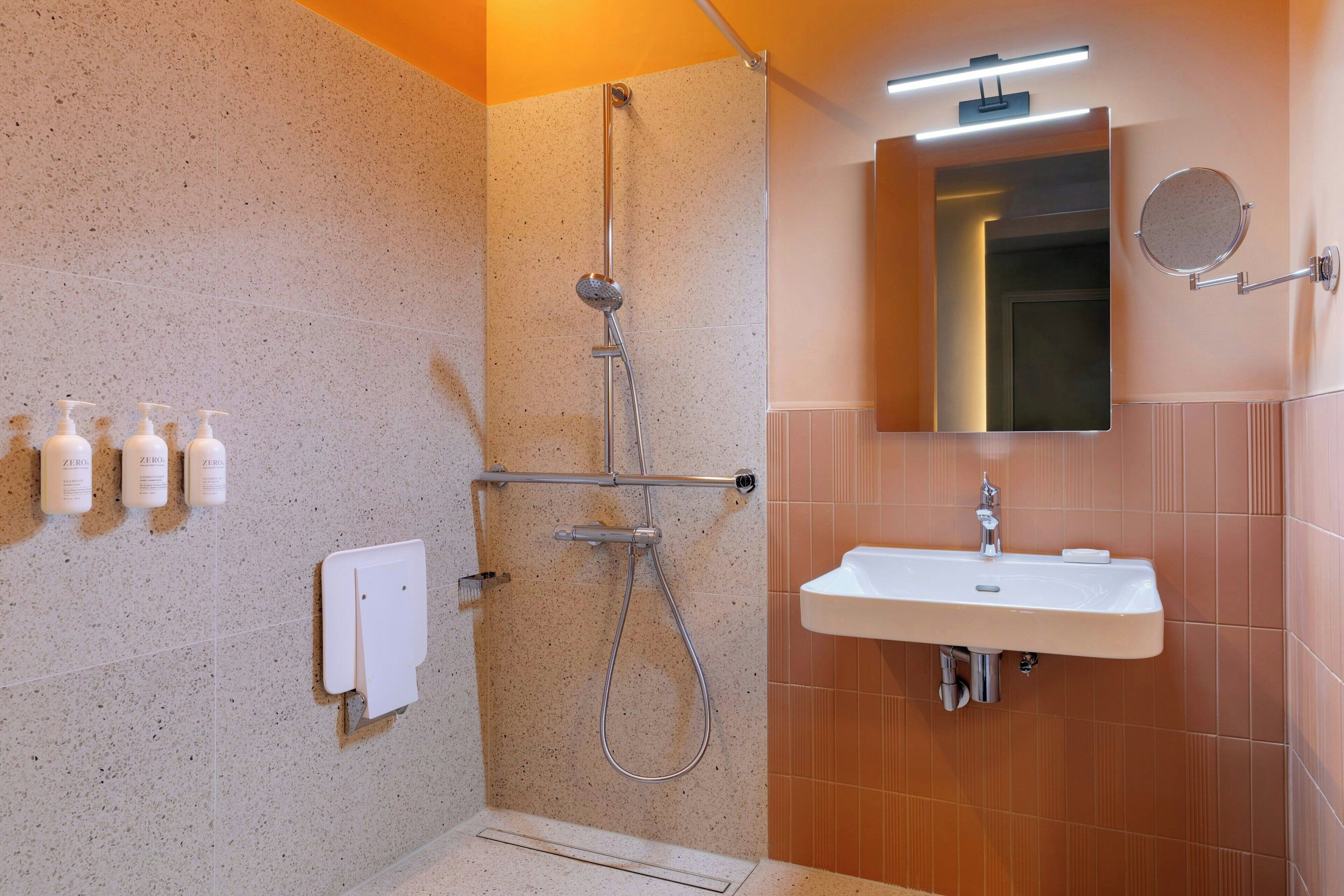 A modern bathroom with a shower, sink, and mirror.