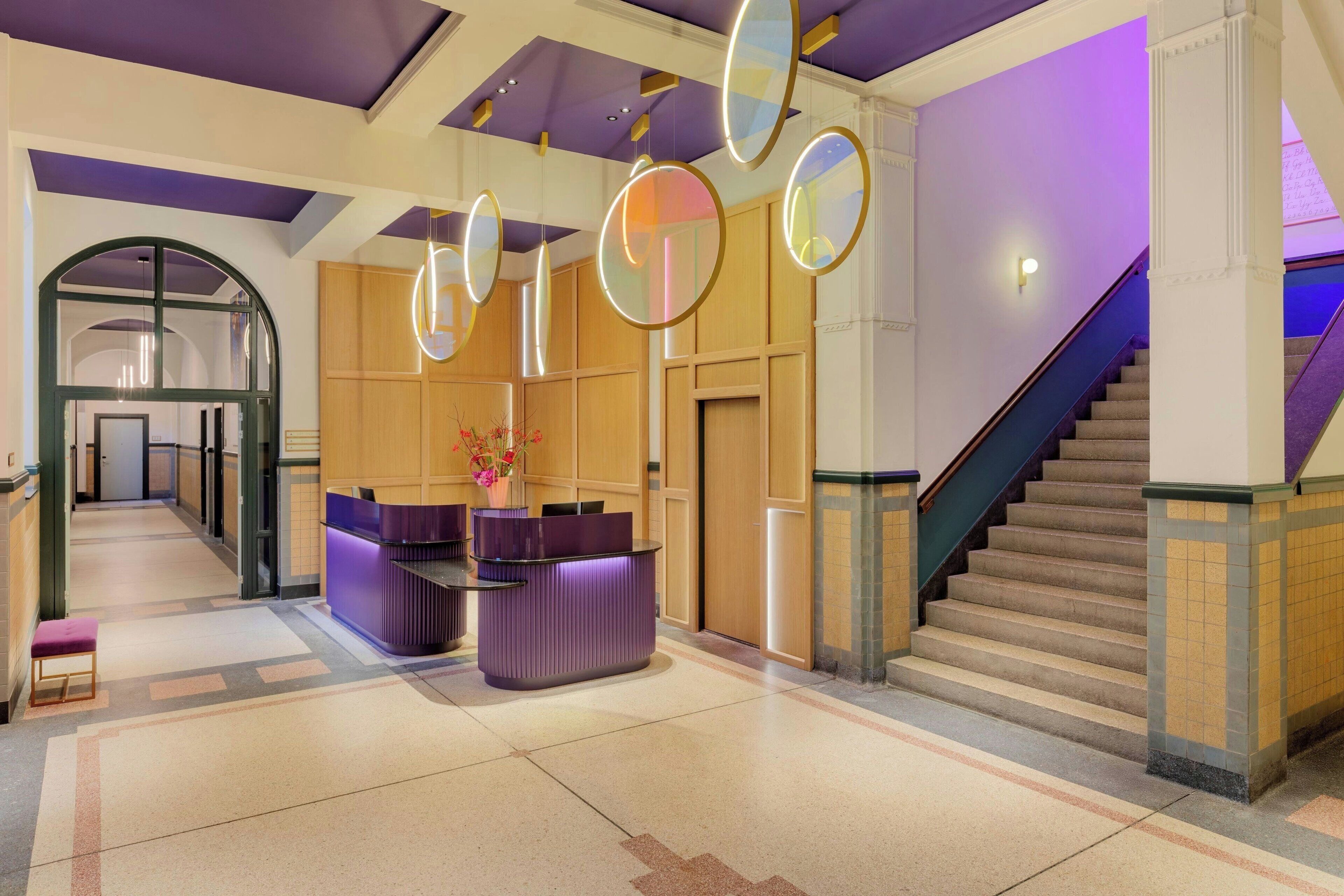 A reception area with a reception desk, a staircase, and a hallway leading to another room.