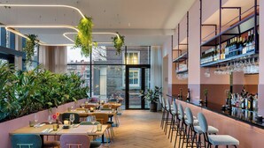 Un ristorante moderno con zona bar, pavimento in legno e piante da interno.