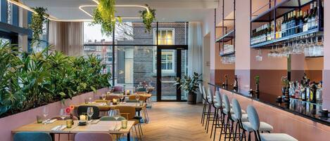 Un restaurante moderno con barra, suelo de madera y plantas de interior.