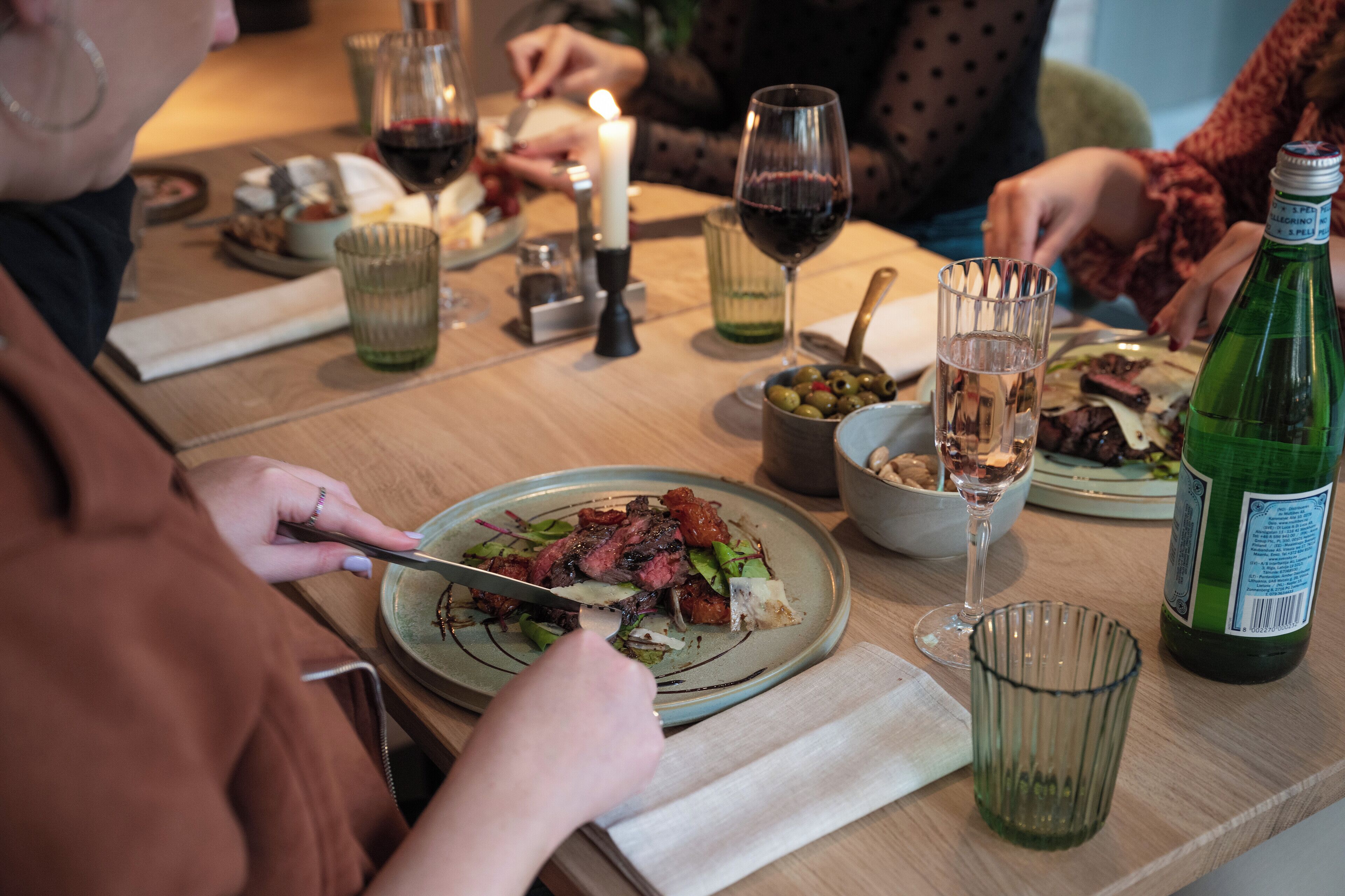 A dining table with plates of food, glasses of wine, and a candle.
