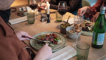 A dining table with plates of food, glasses of wine, and a candle.