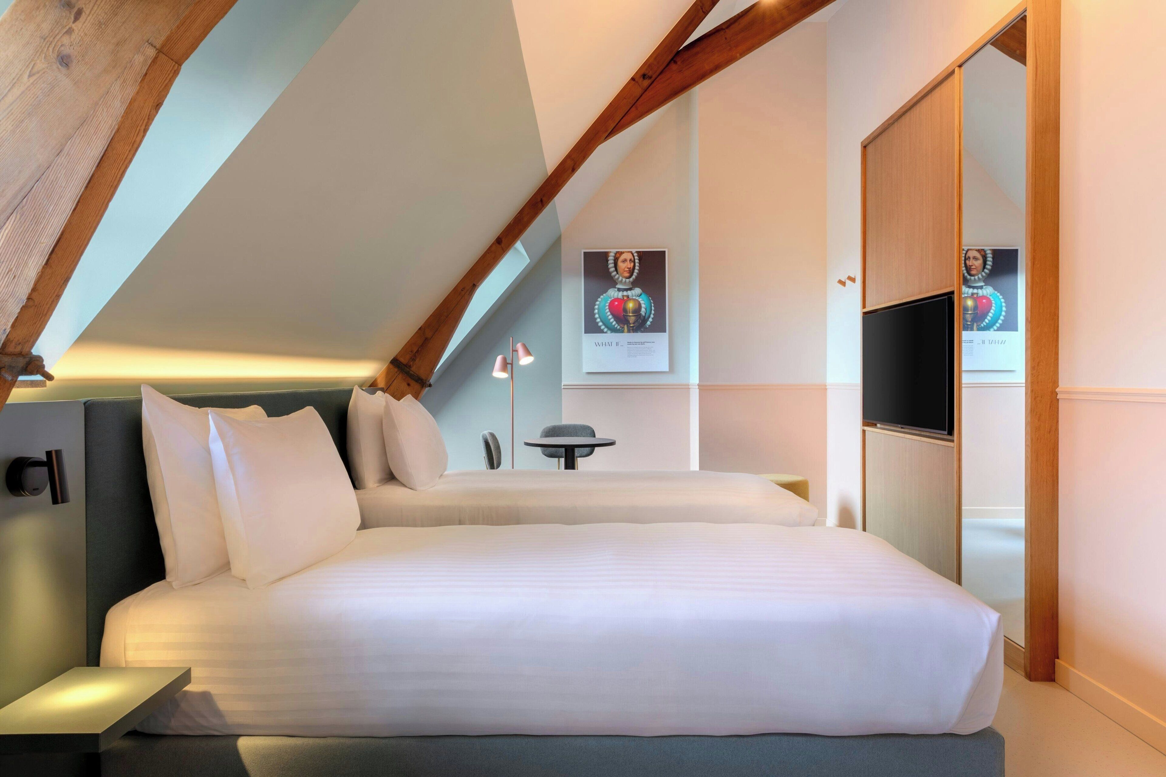 A modern hotel room with a large bed, a small table, and a TV.