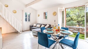 En moderne stue med et glasbord, blå stole, en sofa og en trappe.