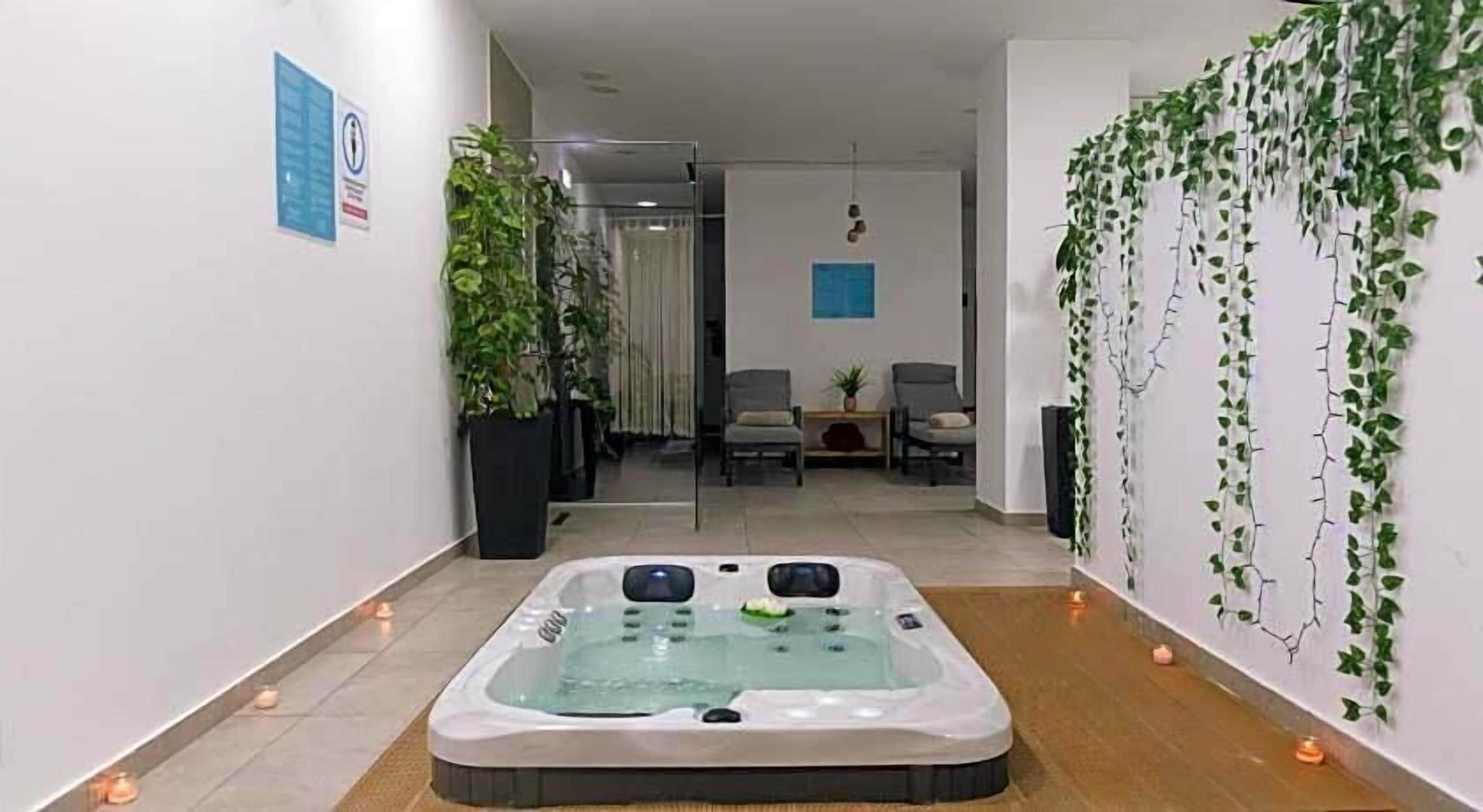 Ein Wellnessbereich mit Whirlpool, Blumentöpfen und Sitzgelegenheiten.