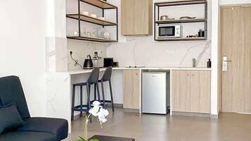Una cocina moderna con microondas, refrigerador y taburetes de bar.