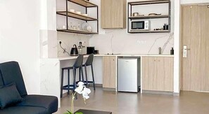 Eine moderne Küche mit Mikrowelle, Kühlschrank und Barhocker.