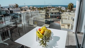A balcony with a table featuring fruits and a clear view of the cityscape and ocean. - Caramela Luxury Apartments (Ayia Napa)