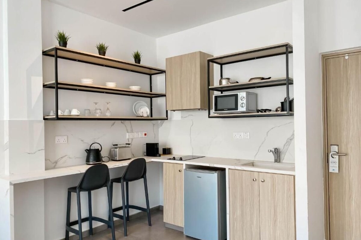 A modern kitchen with built-in appliances, wooden cabinets, and a countertop with bar stools.