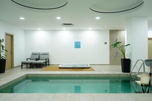 Una piscina con hidromasaje, dos sillas de descanso y plantas en macetas.