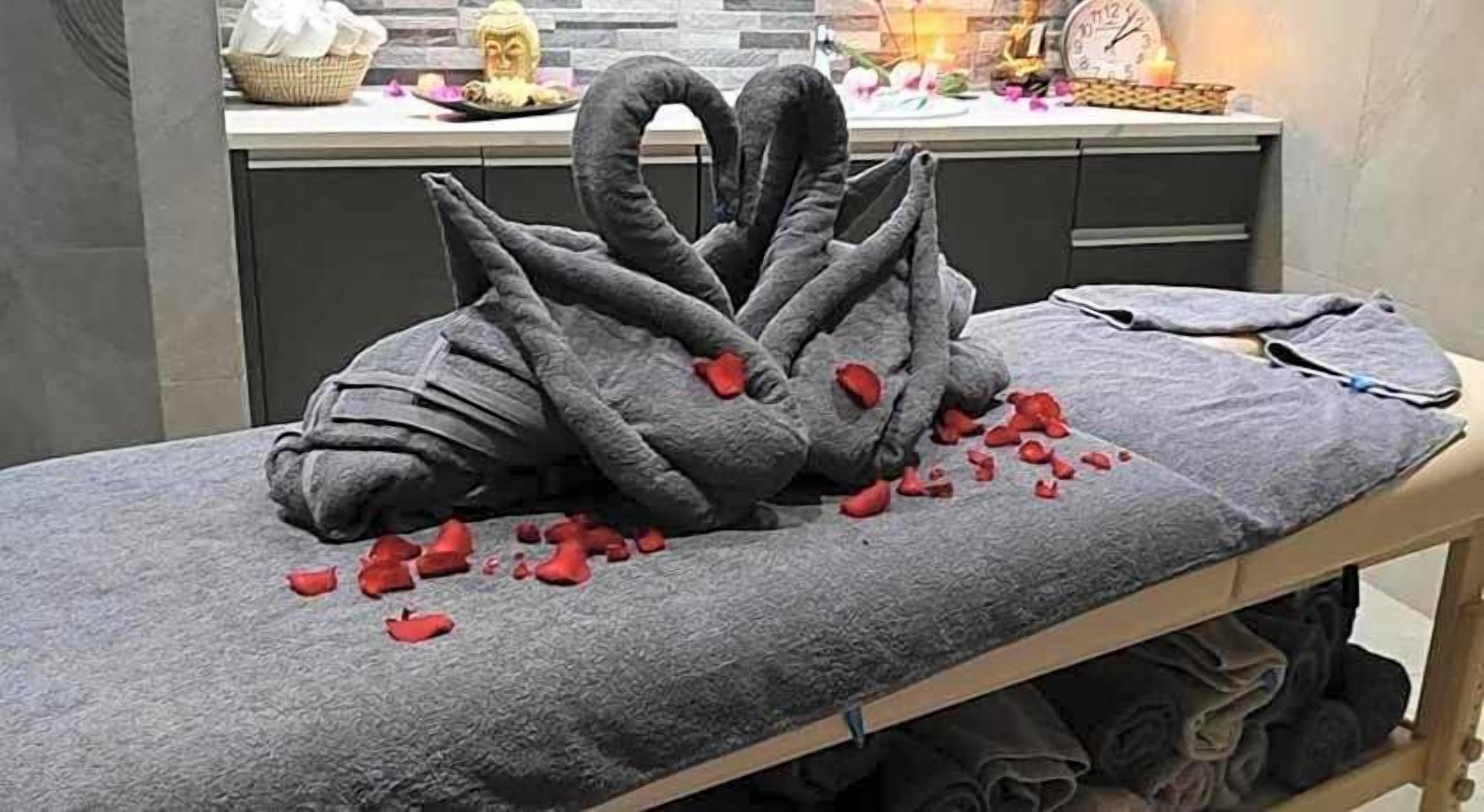 A massage table with a towel and a decorative swan sculpture made of stones.