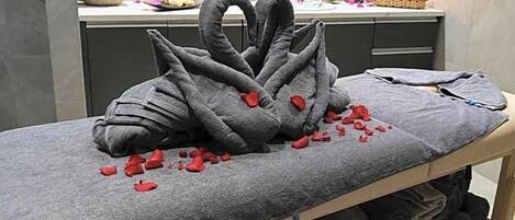 Una mesa de masaje con una toalla y una escultura decorativa de cisne hecha de piedras.