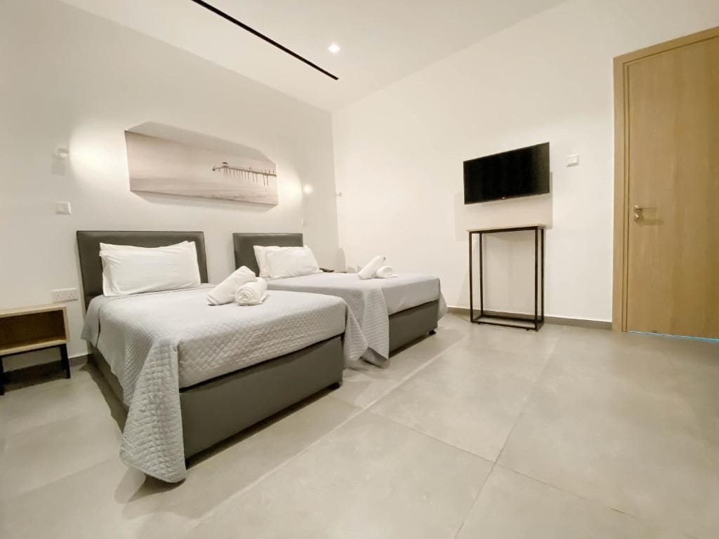 Habitación de hotel moderna con dos camas, un televisor de pantalla plana y una puerta de madera.