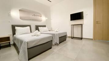 A modern hotel room with two beds, a flat-screen TV, and a wooden door.